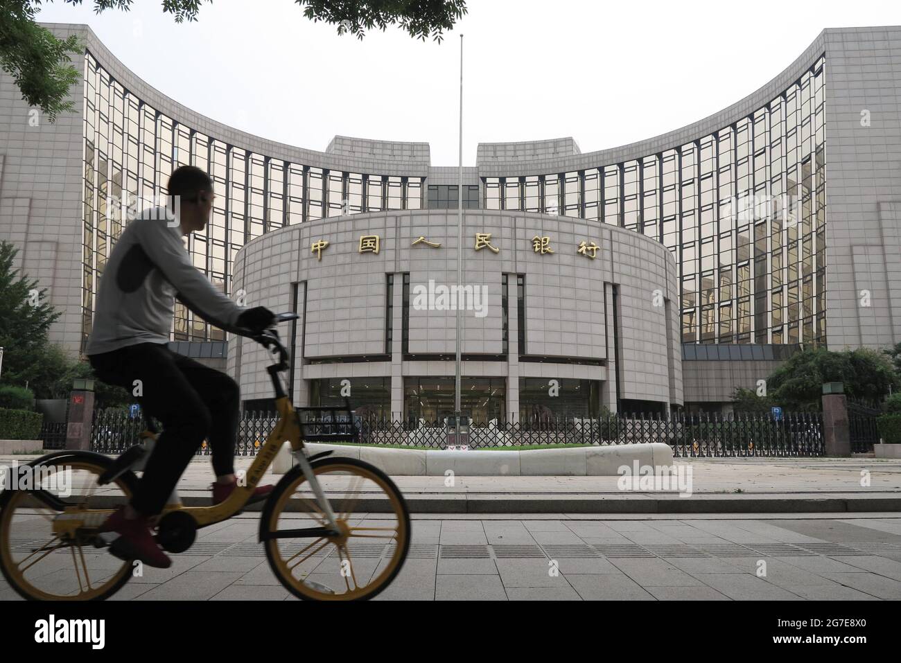 Peking, China. Juli 2021. Ein Mann fährt mit dem Fahrrad am Hauptsitz der  chinesischen Volksbank vorbei. Die chinesische Zentralbank wird die  Mindestreservebedarfquoten (RRR) ab Juli 15 um 0.5 Prozentpunkte senken und  rund