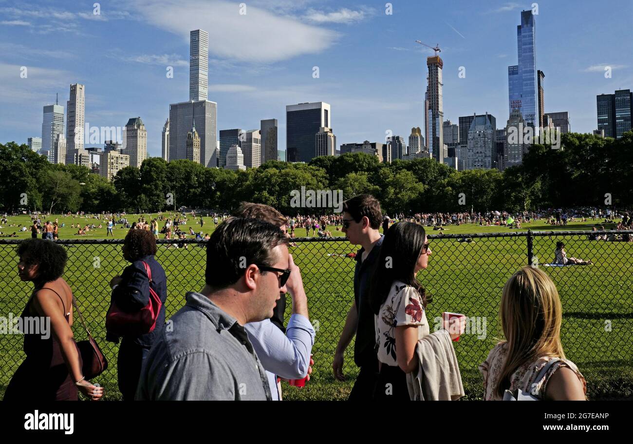 Menschen, die im Central Park mit der Skyline von New York City spazieren. Stockfoto