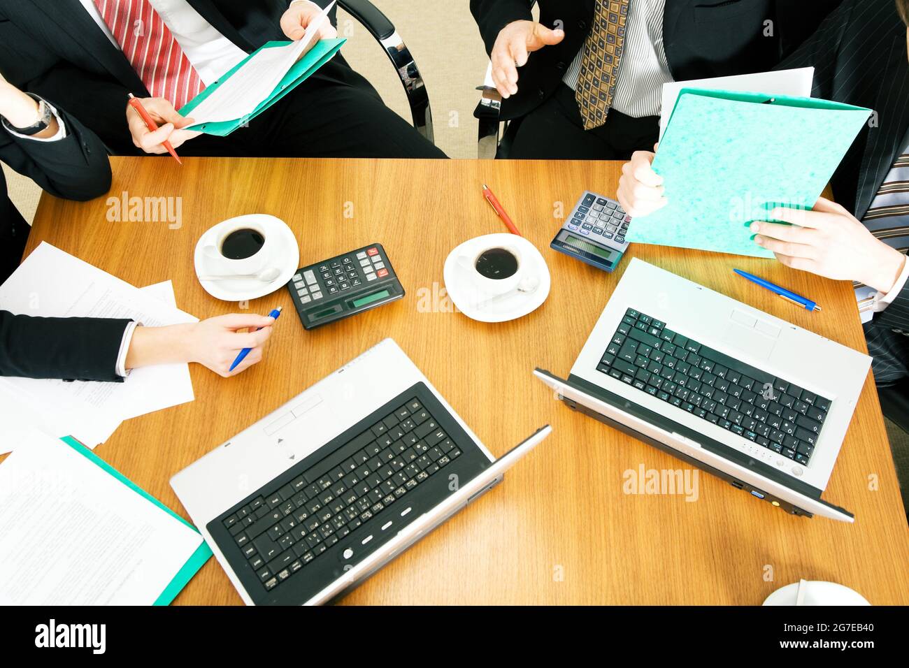 Vier Personen diskutieren oder verhandeln einen Vertrag – und trinken dabei einen Kaffee Stockfoto