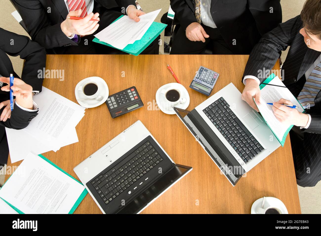 Vier Personen diskutieren oder verhandeln einen Vertrag – und trinken dabei einen Kaffee Stockfoto