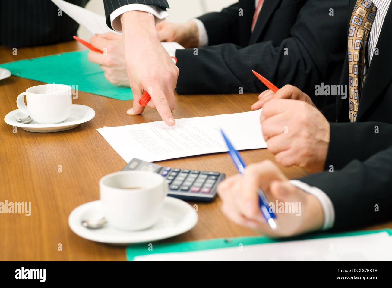 Geschäftsteam diskutiert Dokumente, vermutlich Verträge oder Nummern, Nahaufnahme Stockfoto