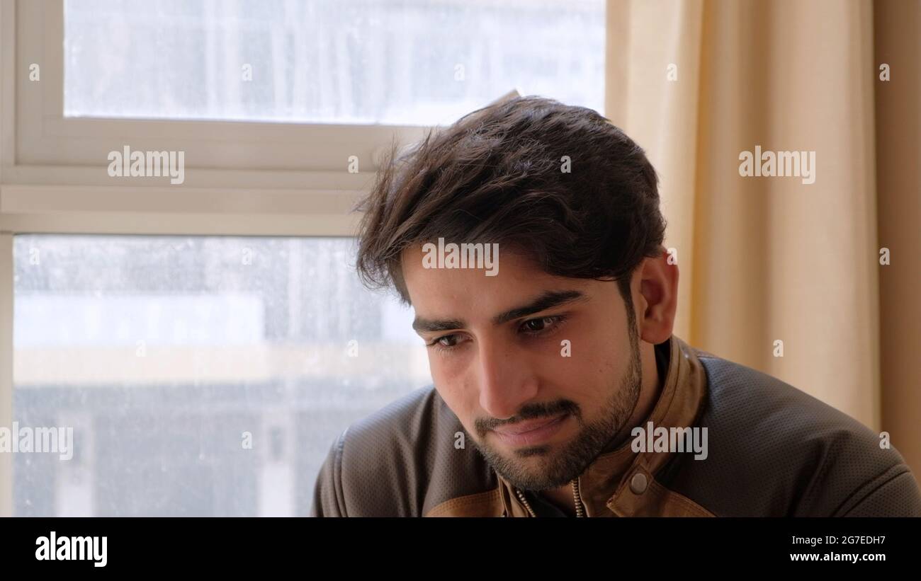 Nahaufnahme eines Indianers in einer Lederjacke, der vor den Fenstern sitzt Stockfoto