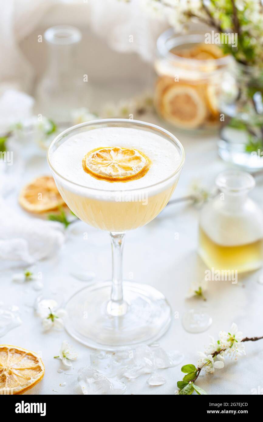 Ein Gin-Sour mit Bergamotte und Kamille, garniert mit Eiweiß-Schaum und einer Scheibe getrockneter Zitrone Stockfoto