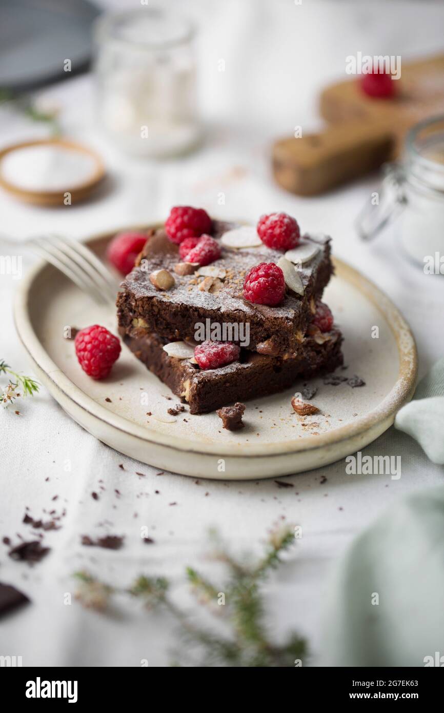 Schokoladen-Brownies, gestapelt, mit Himbeeren auf einem weißen Teller Stockfoto