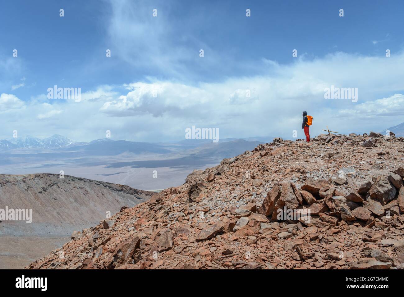 Ein Mann auf dem Gipfel des Vulkans Siete Hermanos, der sich vor einer atemberaubenden Landschaft in der Atacama-Wüste bei Copiapo glücklich fühlt Stockfoto