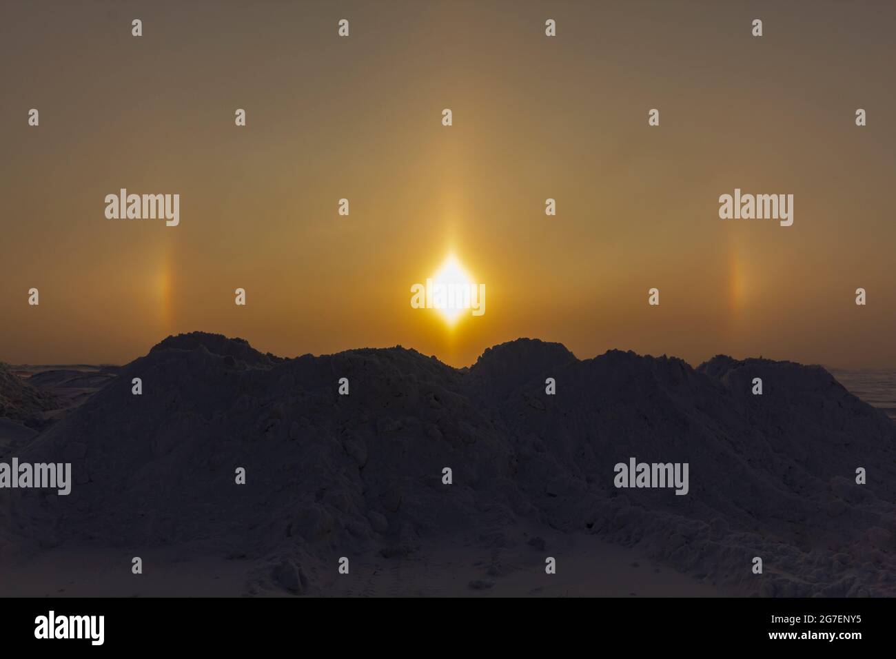 Sonniger optischer Halo-Effekt am frühen Morgen auf dem Hintergrund von Schneemügeln. Das Konzept der Untersuchung der Umwelt. Stockfoto