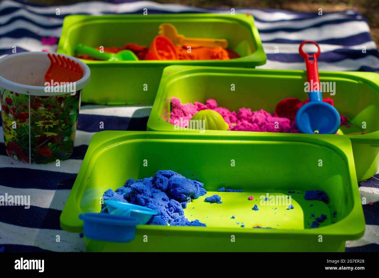 Kinder kinetischer Sand verschiedener Farben in grünen Bädern für die Entwicklung bei Kindern der nützlichen Fähigkeiten. Stockfoto
