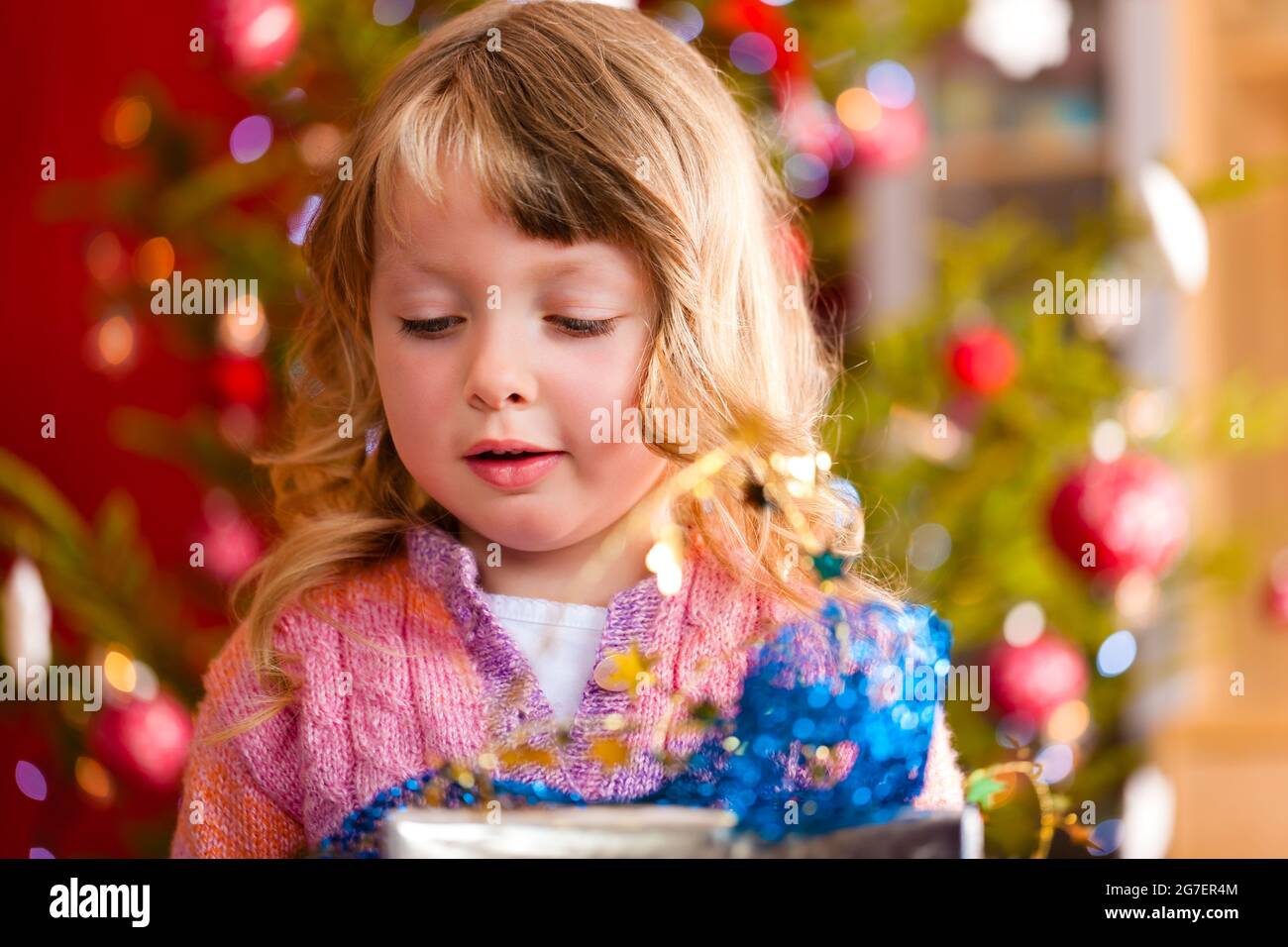 Weihnachten - glückliches kleines Mädchen mit Weihnachtsgeschenk am Heiligabend Stockfoto