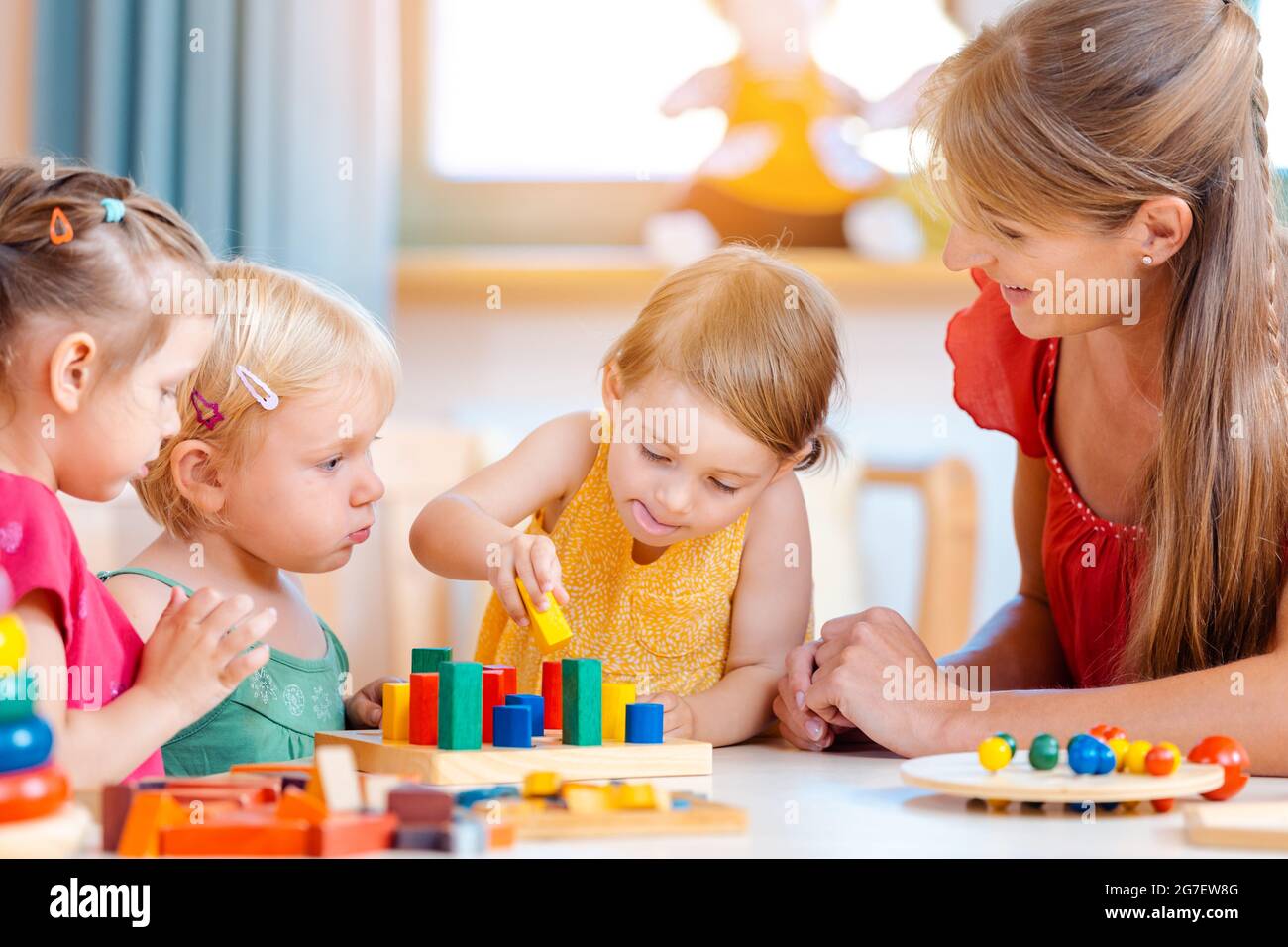 Gruppe von Kindern und Lehrer spielen praktische Spiele im Kindergarten Stockfoto