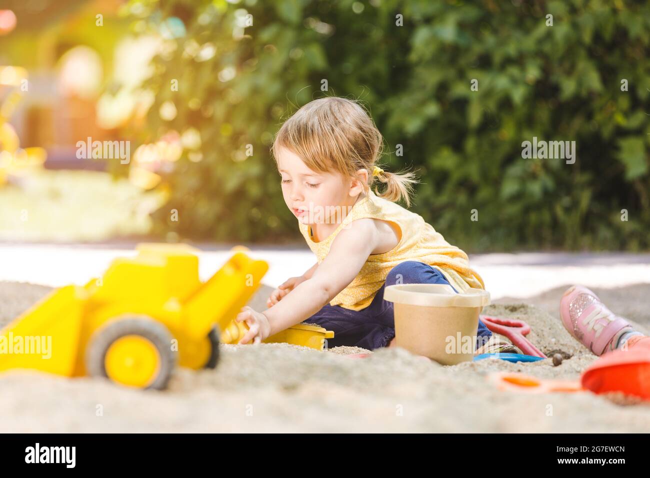 Kleines Mädchen mit viel Spaß mit ihrem Spielzeug spielen in der Sandbox im Freien Stockfoto