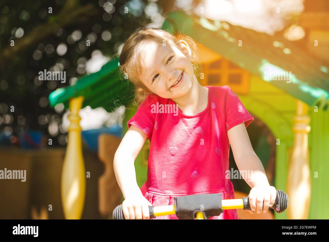 Mädchen Kind spielt im Freien in der Sonne lächelt in die Kamera Stockfoto