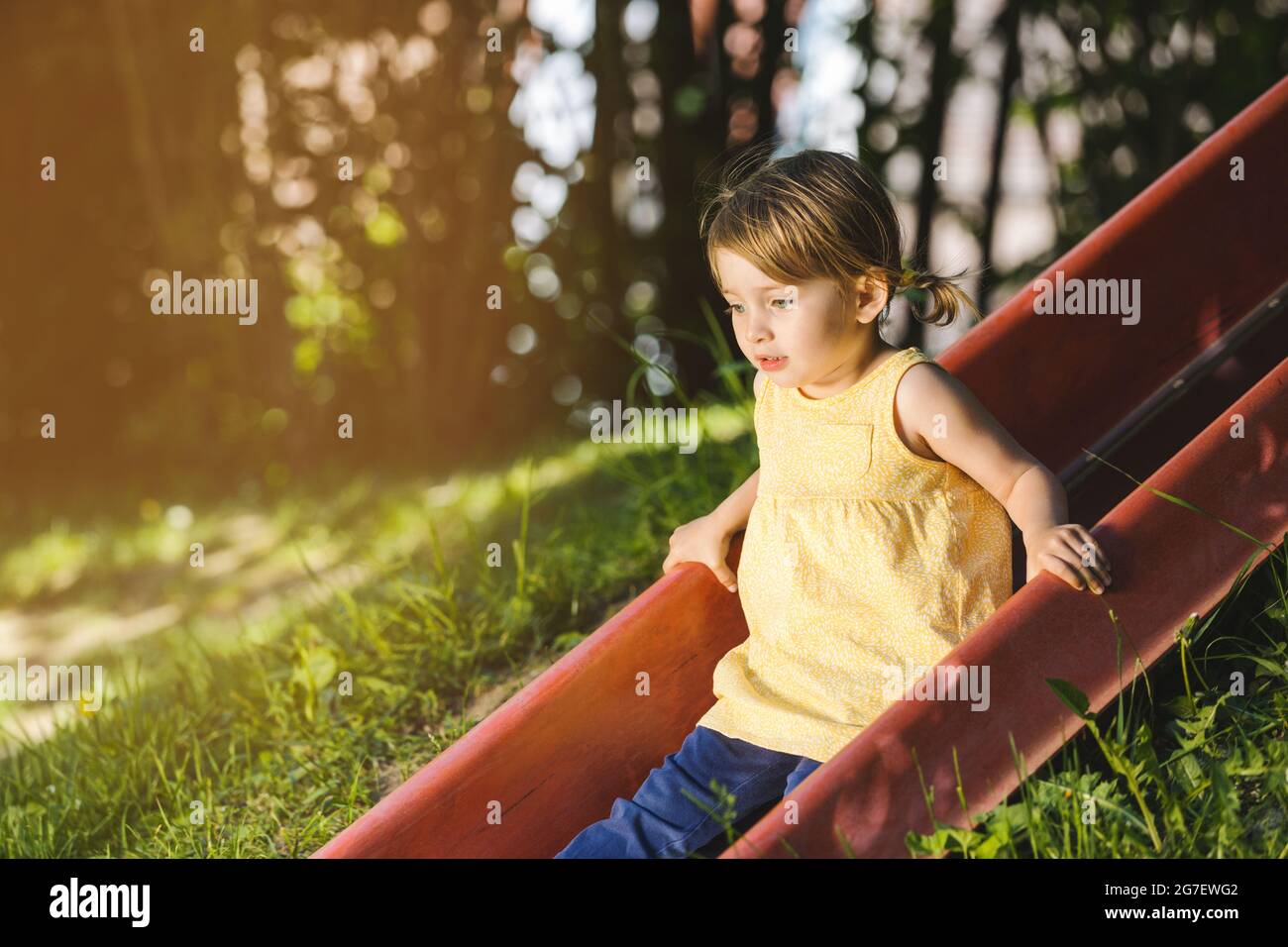 Kleines Mädchen auf dem Spielplatz auf einer Rutsche Blick in Kamera Stockfoto