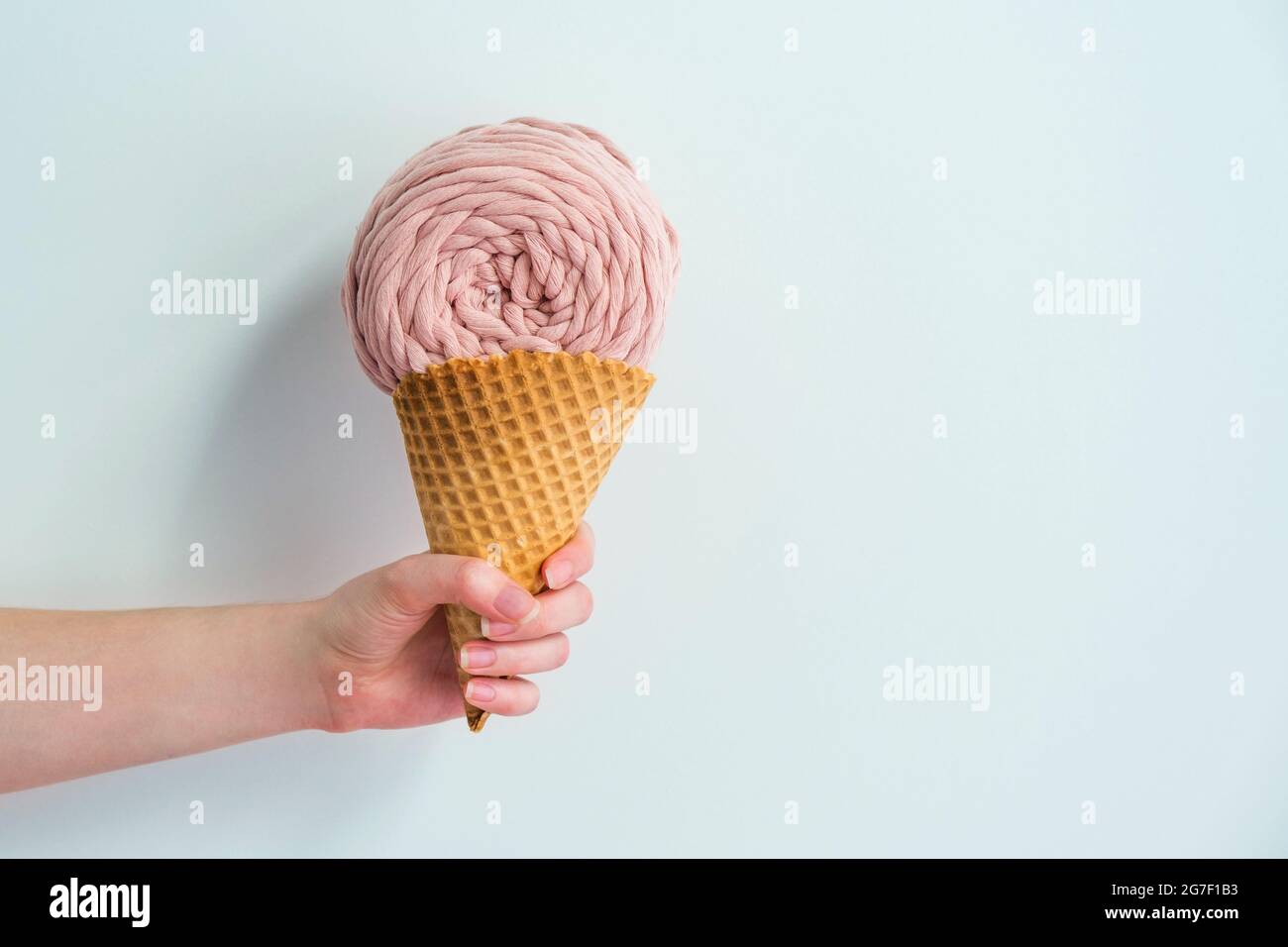 Rosa runde Makramigarn-Skein im Eiskegel in der Frauenhand. Kreative Makrame Strickidee Stockfoto