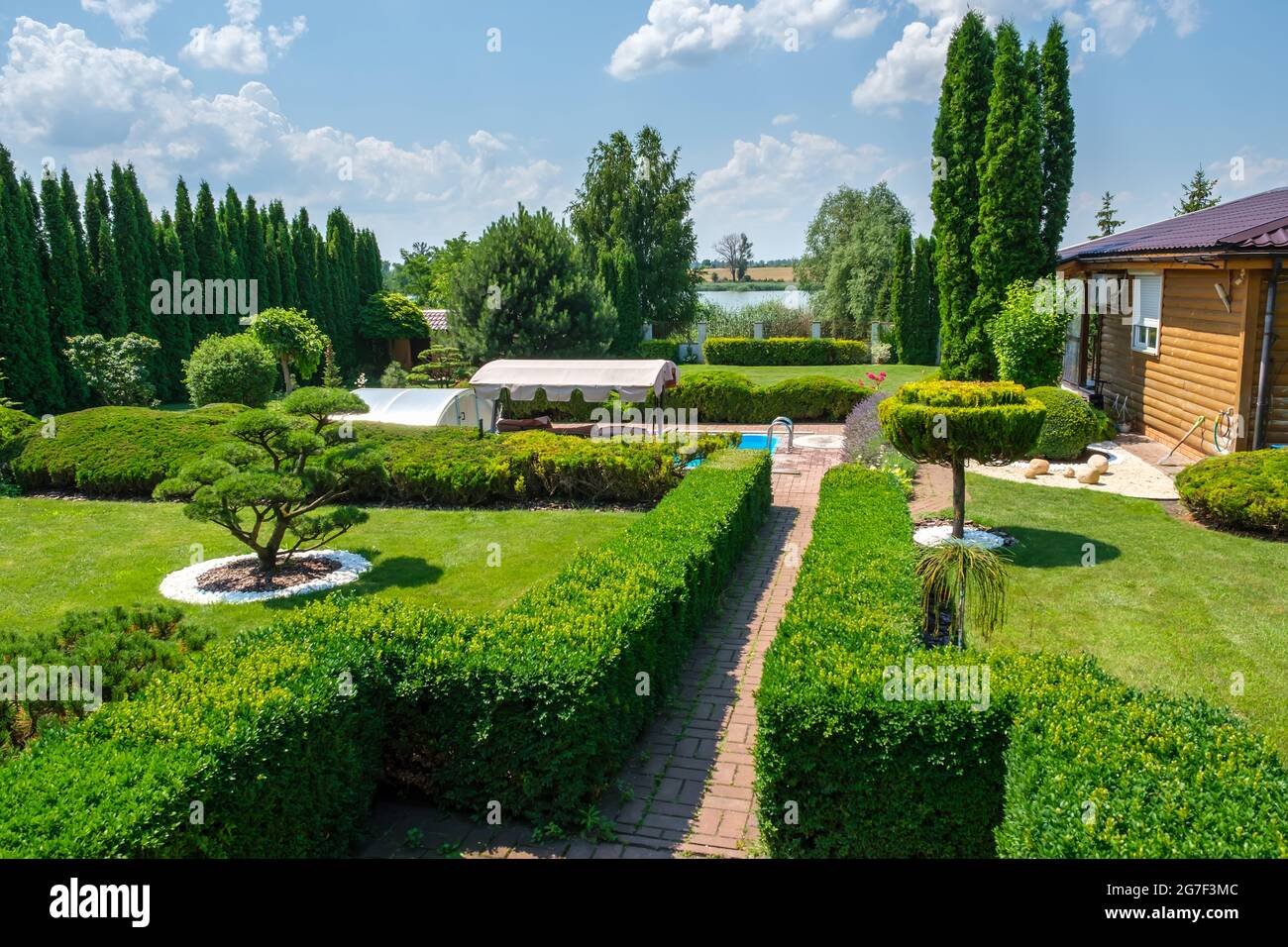 Schöner Garten im Hinterhof mit schön getrimmten Bäumen, Büschen und Steinen. Stockfoto