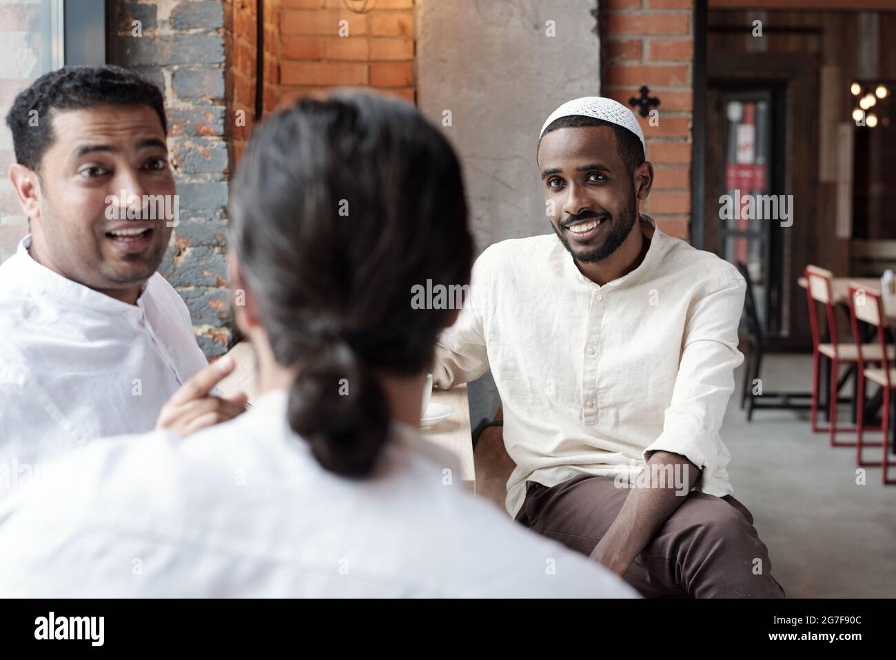 Eine Gruppe islamischer schwarzer Männer, die im Café sitzen und Nachrichten diskutieren, während sie Zeit miteinander verbringen Stockfoto