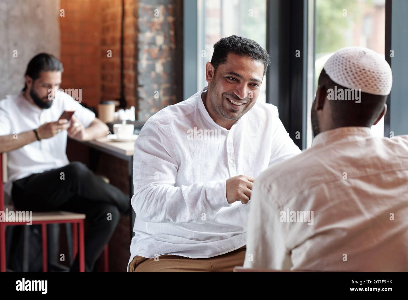Positive muslimische Männer, die im Café an der Theke sitzen und sich unterhalten Stockfoto