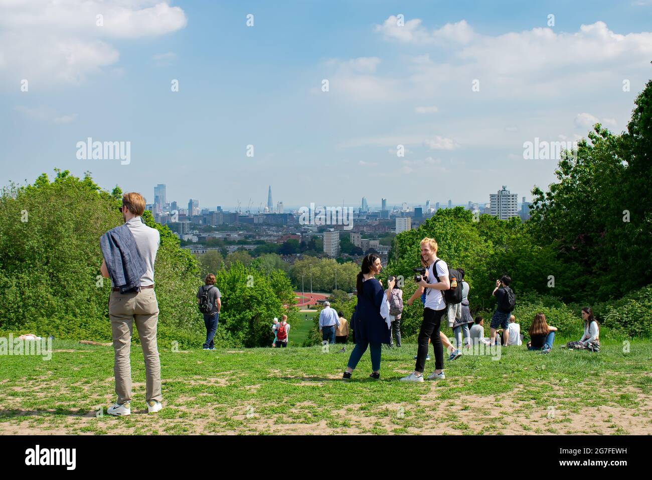 Besucher stehen und genießen den Blick vom Parliament Hill Viewpoint in Hampstead Heath. Der Shard, St Paul's und die City of London sind sichtbar. Stockfoto