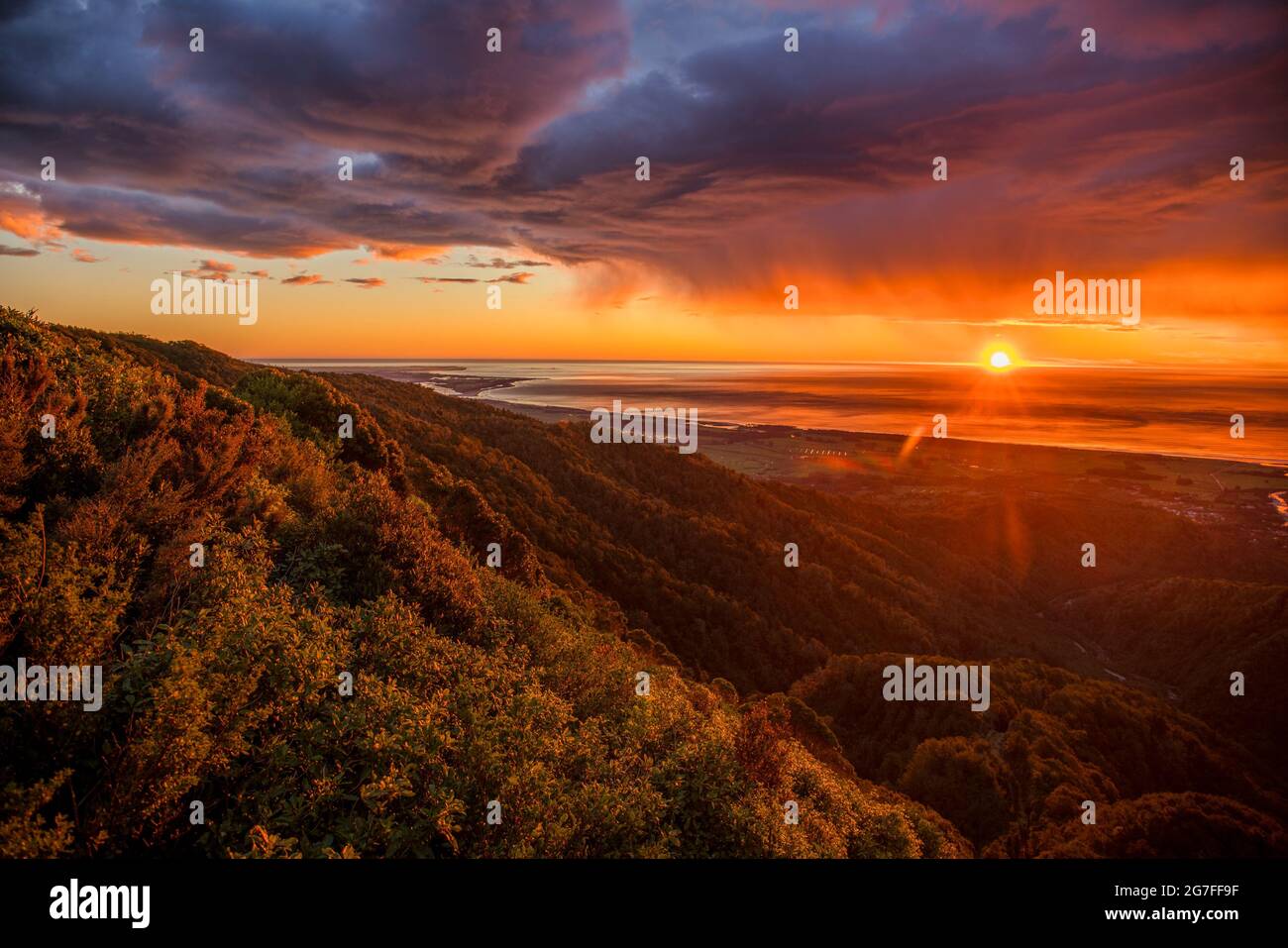 Dramatisches, feuriges Wolkenbild-Panorama bei Sonnenuntergang von der Hügelspitze der historischen Denniston Coal Mine in der Nähe von Westport an der Westküste NZ Stockfoto