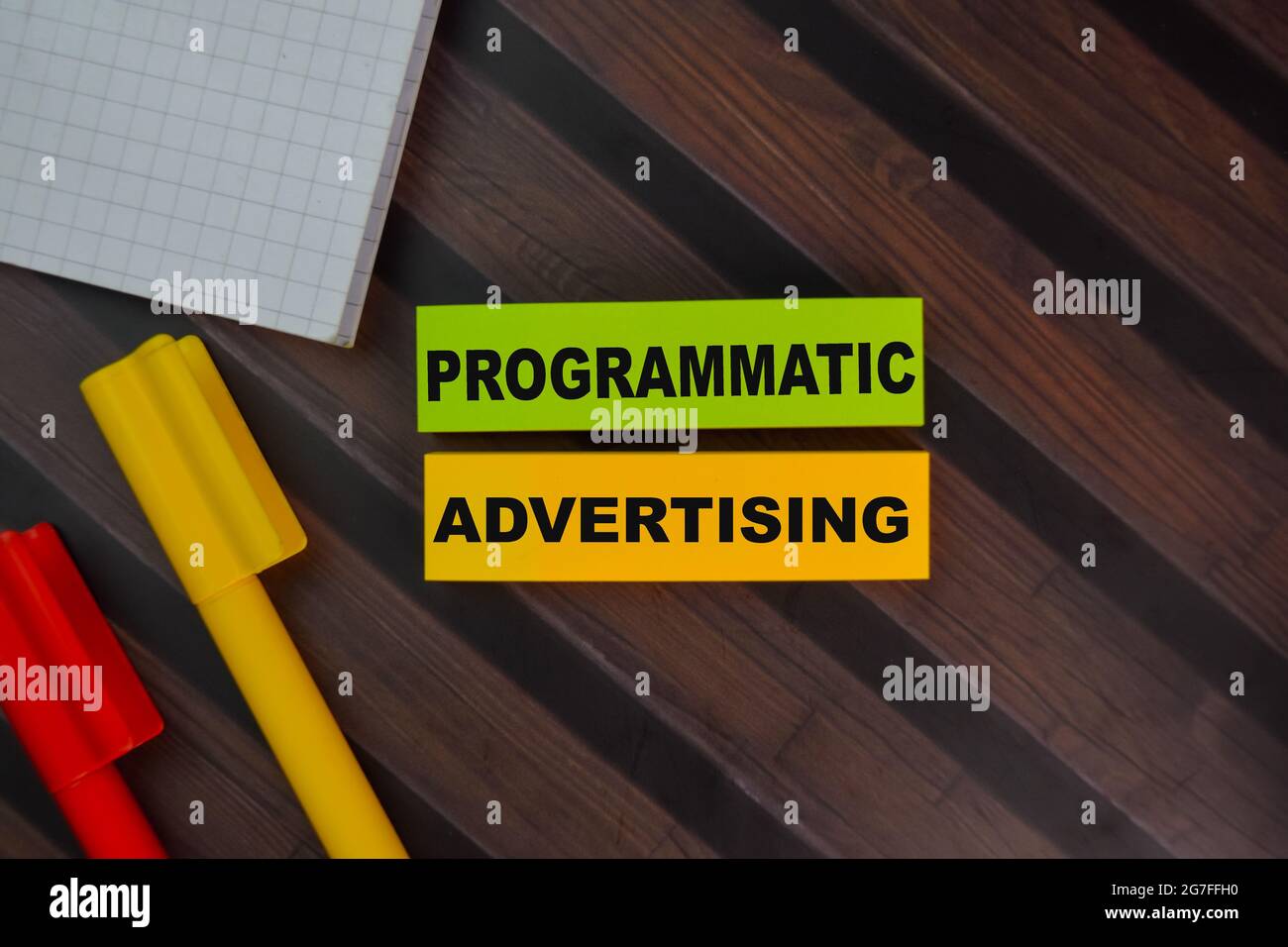 Programmatic Advertising schreiben auf Haftnotizen isoliert auf Holztisch. Stockfoto