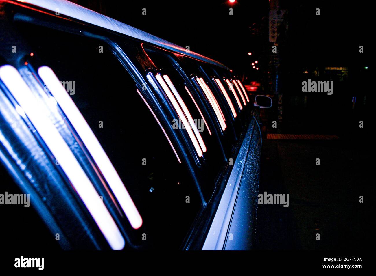 Eine Long Stretch-Limousine, die in einer regnerischen Nacht mit Wassertröpfchen bedeckt ist Stockfoto