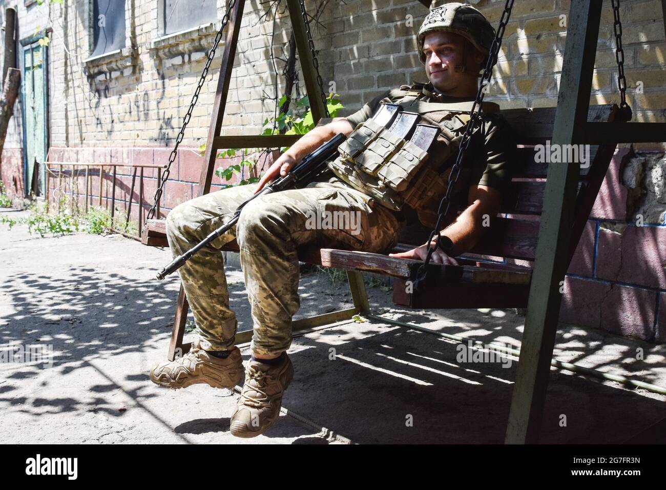 Ukrainischer Soldat sitzt auf einer Holzbank in Marinka. Marinka, eine kleine Stadt in der Ostukraine, liegt an der Front des Konflikts. Nach einem umfassenden Waffenstillstand in der zweiten Jahreshälfte 2020 haben die Spannungen in der Ostukraine im Jahr 2021 zugenommen. Die Ukraine verfügt mit rund 200,000 aktiven Soldaten über die drittgrößte Armee Europas. Stockfoto