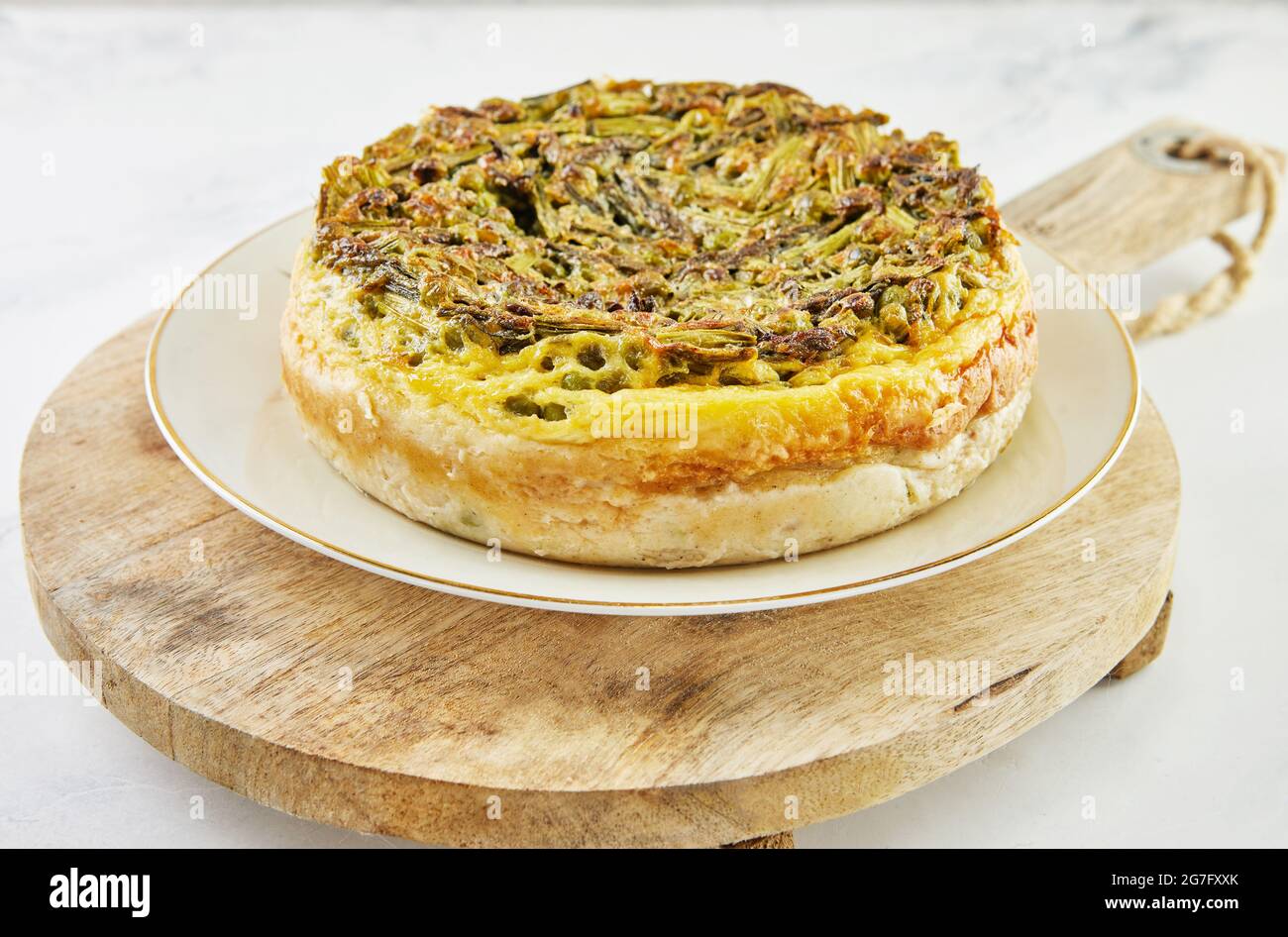 Pie mit Spargel und Erbsen auf Teller und Holzständer. Schritt für Schritt Rezept Stockfoto
