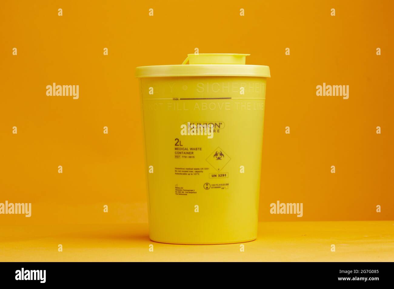 ZUTPHEN, NIEDERLANDE - Jul 04, 2021: Closeup kleiner Spritzensammler auf nahtlosem gelben Hintergrund zur sicheren Entsorgung von Nadel- und Arzneimittelrückständen wi Stockfoto
