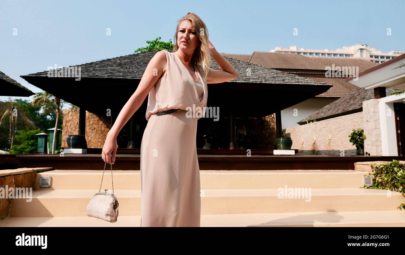 Osteuropäische kaukasische Frau mittleren Alters blondes Haar helle Haut blassen Teint tragen weißes Sommerkleid Lässige Kleidung Tag posiert am Pool Stockfoto