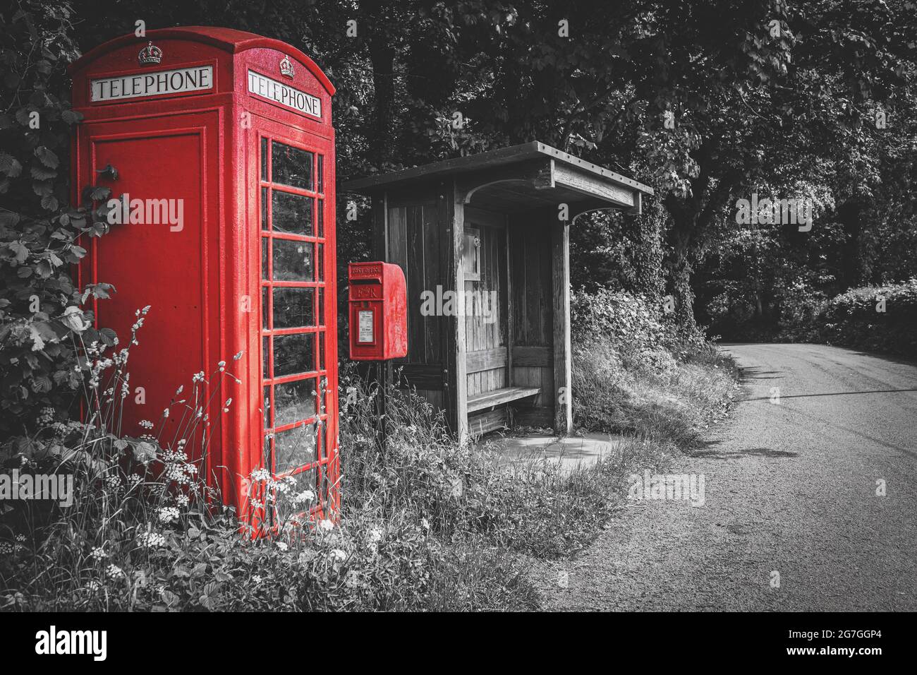 Traditionelle rote britische Telefonzelle, Briefkasten und hölzerne Bushaltestelle, selektive Farbe auf schwarzem und weißem Hintergrund, keine Menschen. Wales, Großbritannien Stockfoto