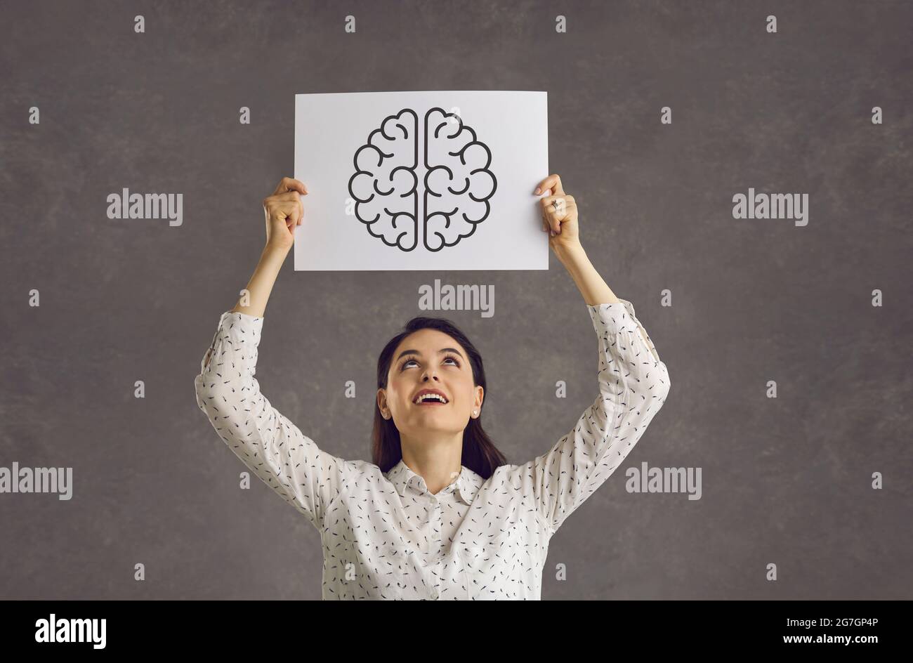 Glückliche Frau, die das Bild des Gehirns als Symbol für psychische Gesundheit und intellektuelle Entwicklung hält Stockfoto