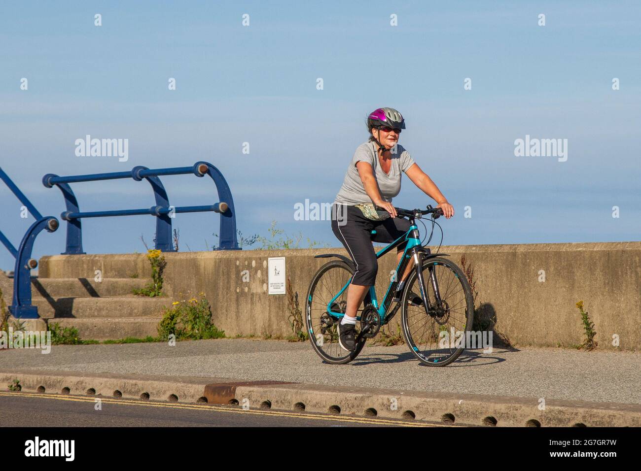 Southport, Merseyside. Vereinigtes Königreich Wetter 14 Juli 2021. Der Sommerhimmel und die leichten Winde im Badeort, während die Menschen am frühen Morgen die Sonne an der Strandpromenade genießen. Kredit; MediaWorldImages/AlamyLiveNews Stockfoto