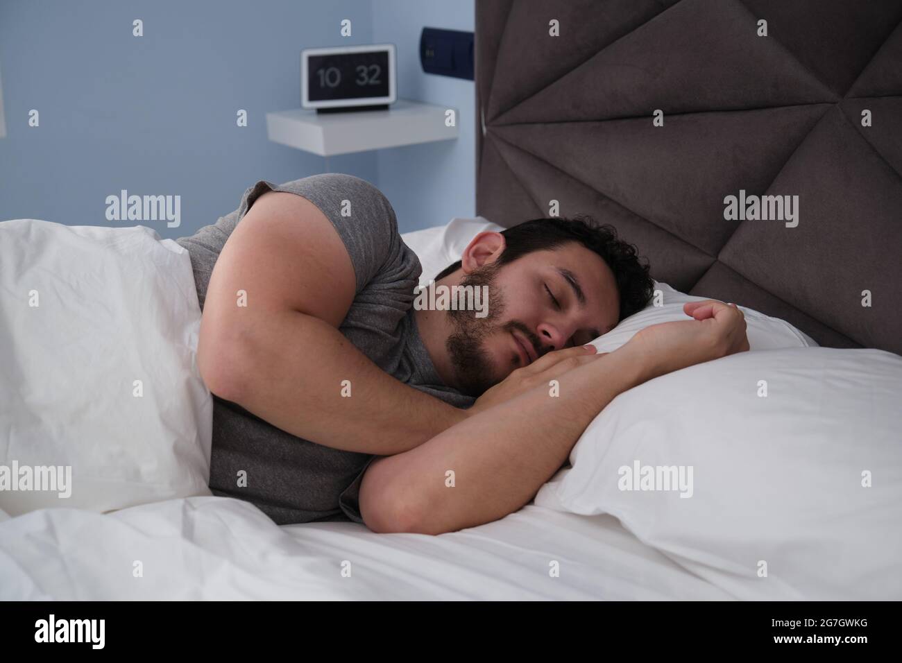 Junger latein, der am späten Morgen im Bett schlief. Digitale Uhr im  Hintergrund Stockfotografie - Alamy