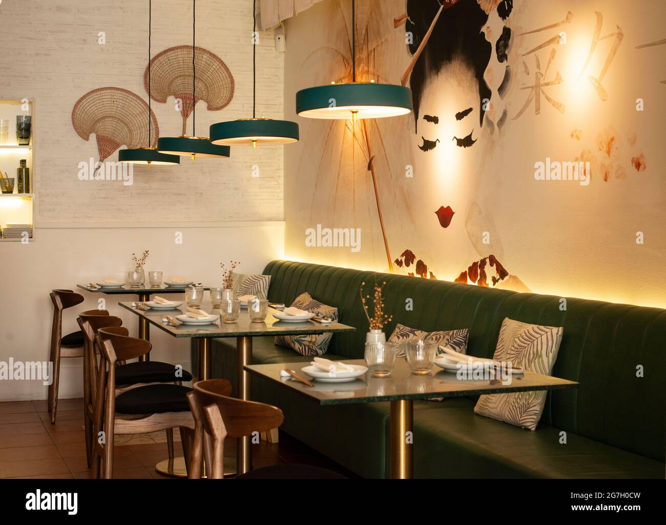 Gemütliches Interieur des asiatischen Restaurants mit komfortablem Sofa und Glastischen, die mit Geschirr serviert werden Stockfoto