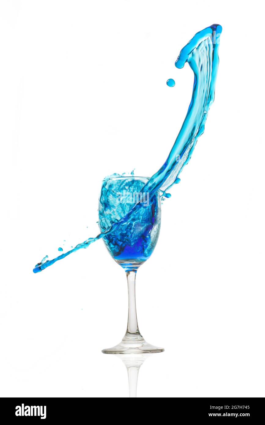 Weinglas auf weißem Hintergrund mit einem blauen Wasserspritzer. Stockfoto