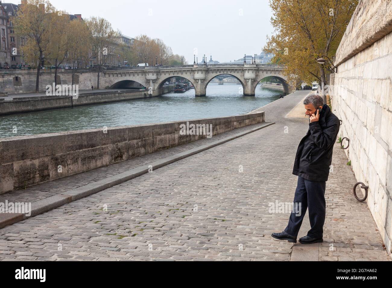 Mann telefonieren auf einem Kai der seine, die Pont Neuf im Hintergrund. Paris, Frankreich Stockfoto