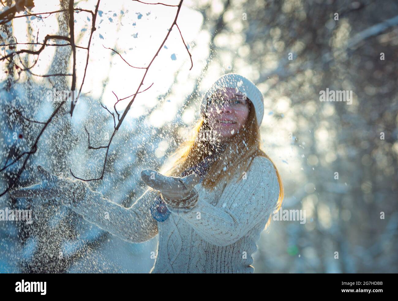 Glückliche Frau spielt mit einem Schnee an sonnigen Wintertagen. Mädchen genießt Winter, frostigen Tag. In den Winterferien spielt eine Frau mit Schnee und wirft weiße, lose s Stockfoto