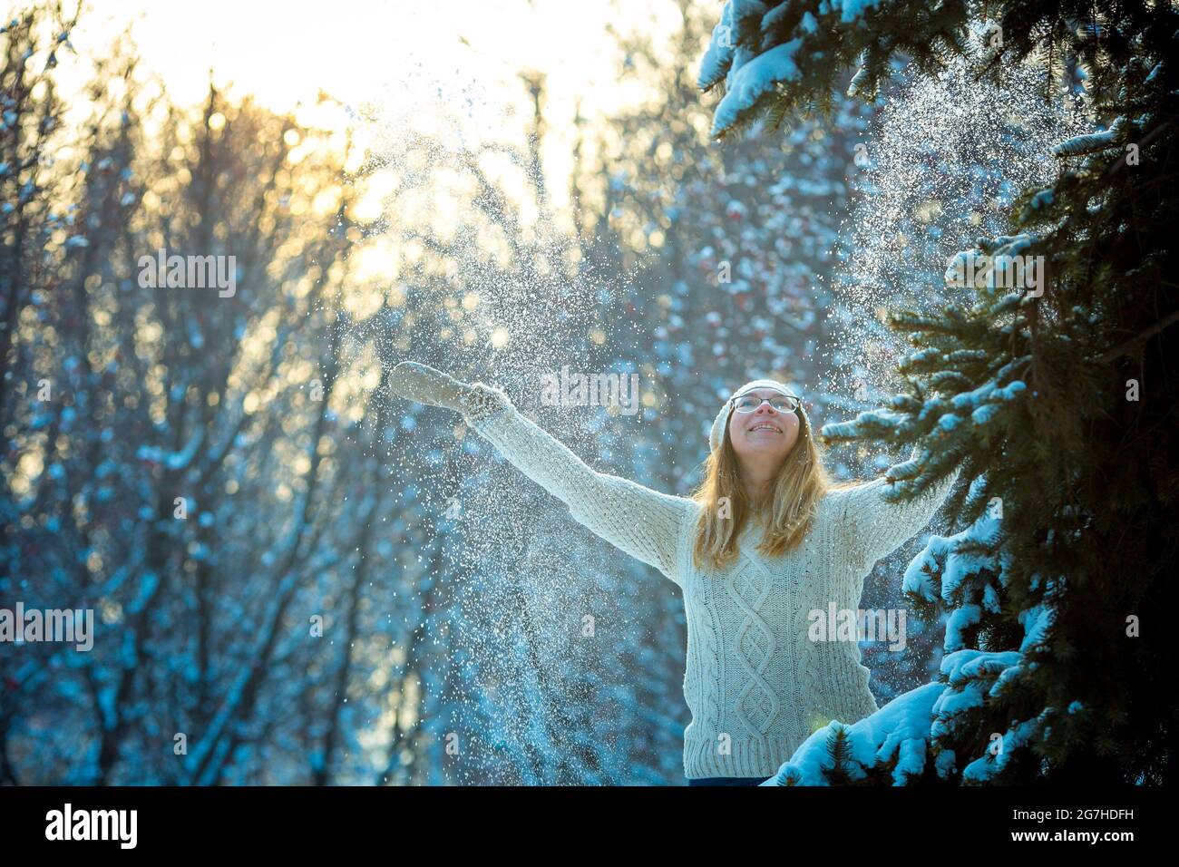 Glückliche Frau spielt mit einem Schnee an sonnigen Wintertagen. Mädchen genießt Winter, frostigen Tag. In den Winterferien spielt eine Frau mit Schnee und wirft weiße, lose s Stockfoto