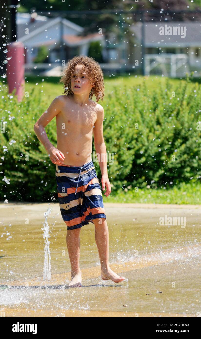 Ein kleiner Junge (9 Jahre) spielt in Quebec City, Kanada, Wasserspiele und Springbrunnen Stockfoto