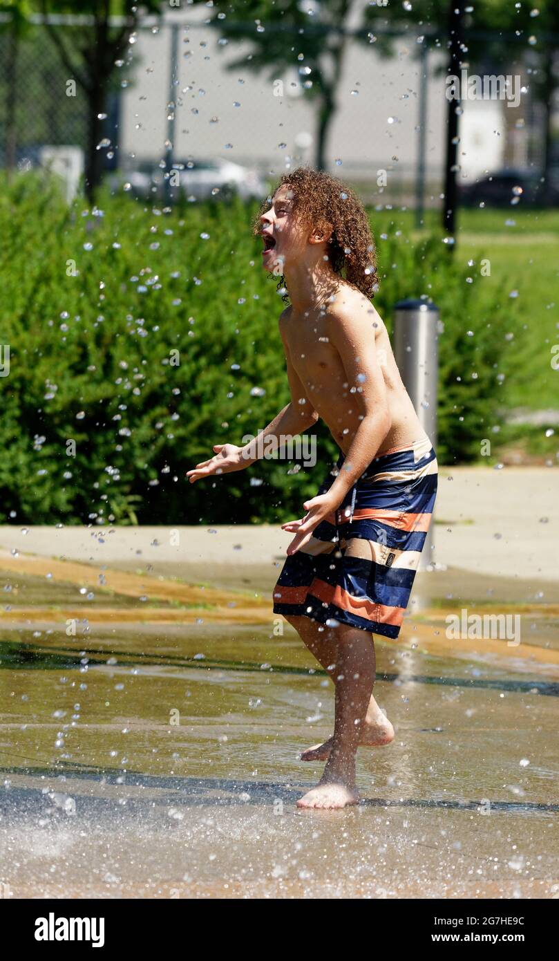 Ein kleiner Junge (9 Jahre) spielt in Quebec City, Kanada, Wasserspiele und Springbrunnen Stockfoto