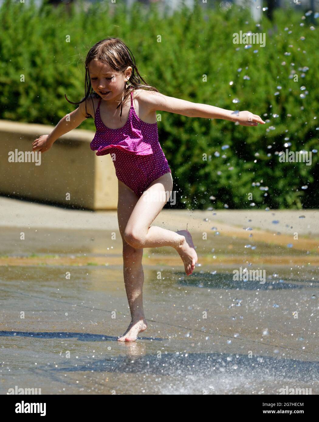 Ein kleines Mädchen (7 Jahre alt), das in Quebec City, Kanada, Wasserspiele und Springbrunnen spielt Stockfoto