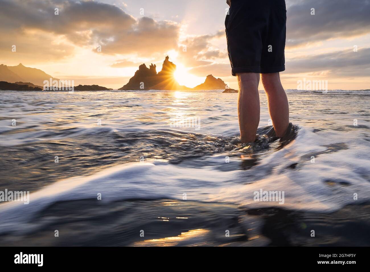 Niedriger Teil des Menschen während der Entspannung im Meer. Schöner Blick auf den Strand von Benijo gegen den Himmel bei schönem Sonnenuntergang. Teneriffa, Kanarische Inseln, Spanien. Stockfoto