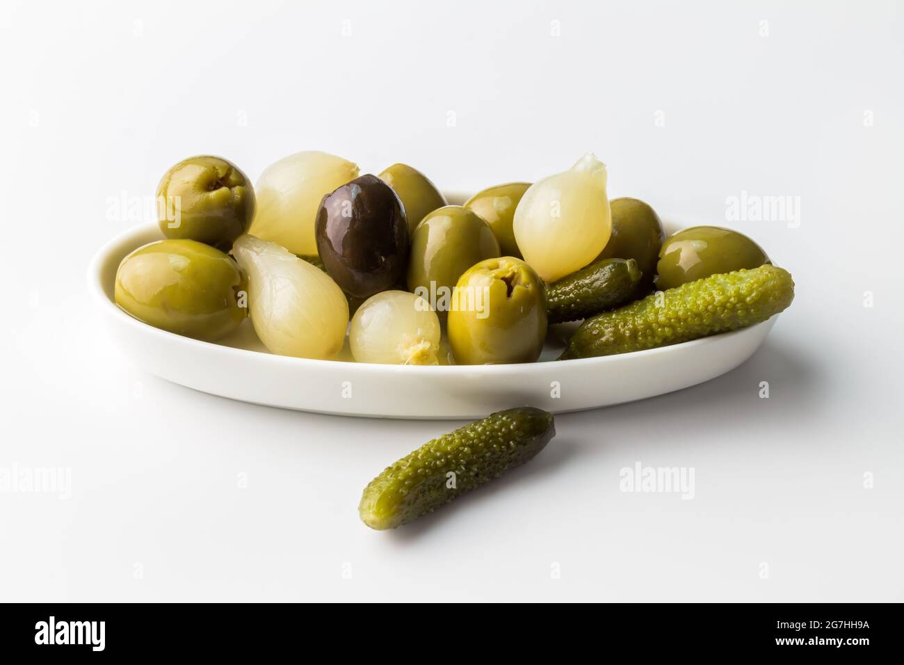 Verschiedene Dill-Gurken, Zwiebeln und Oliven in weißem Teller isoliert auf weißem Hintergrund mit Kopierraum Stockfoto