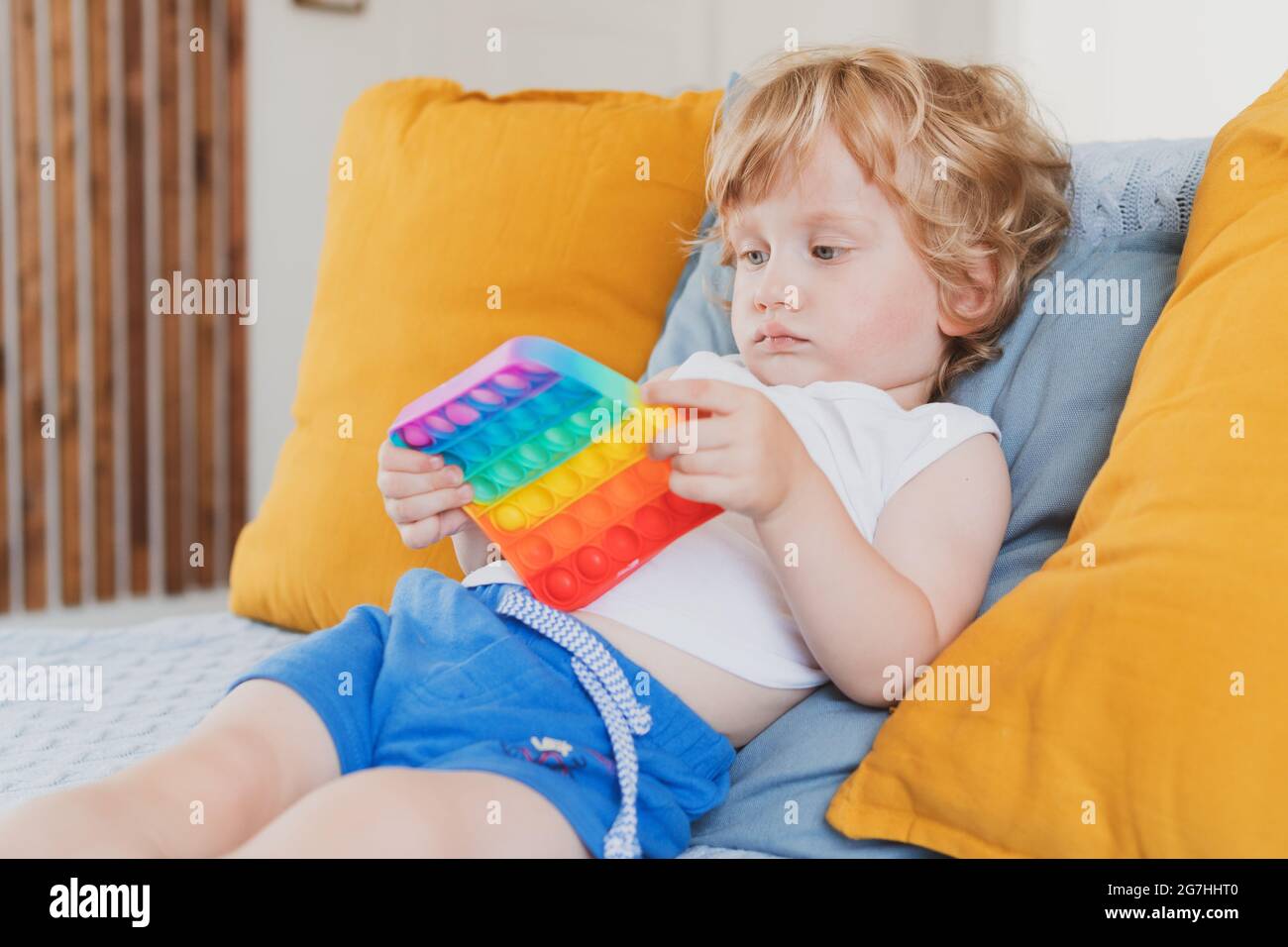 Kleiner Junge hält Anti-Stress sensorische Pop it Spielzeug in der Hand Junges Kleinkind Flechten mit Fidget sensorische Spielzeug Stockfoto