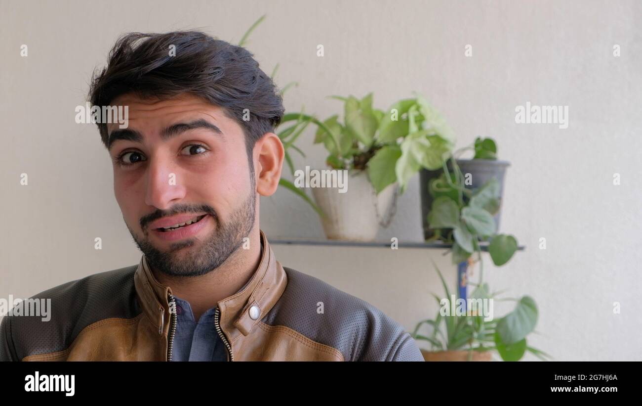 Junger indischer Mann in einer Lederjacke, der einen lustigen Gesichtsausdruck macht Stockfoto