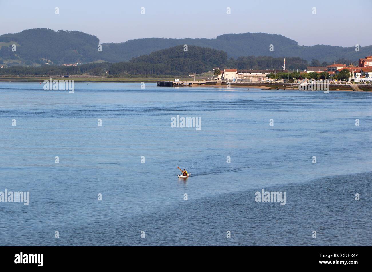 Blick über die Bucht von Santona Cantabria, Spanien, mit einem einflügeligen Kanufahrer, der an einem ruhigen Sommermorgen vor dem Hotel vorbeifährt Stockfoto