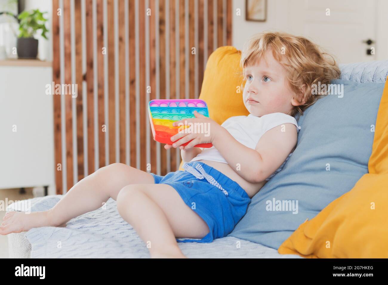 Kleiner Junge hält Anti-Stress sensorische Pop it Spielzeug in der Hand Junges Kleinkind Flechten mit Fidget sensorische Spielzeug Stockfoto