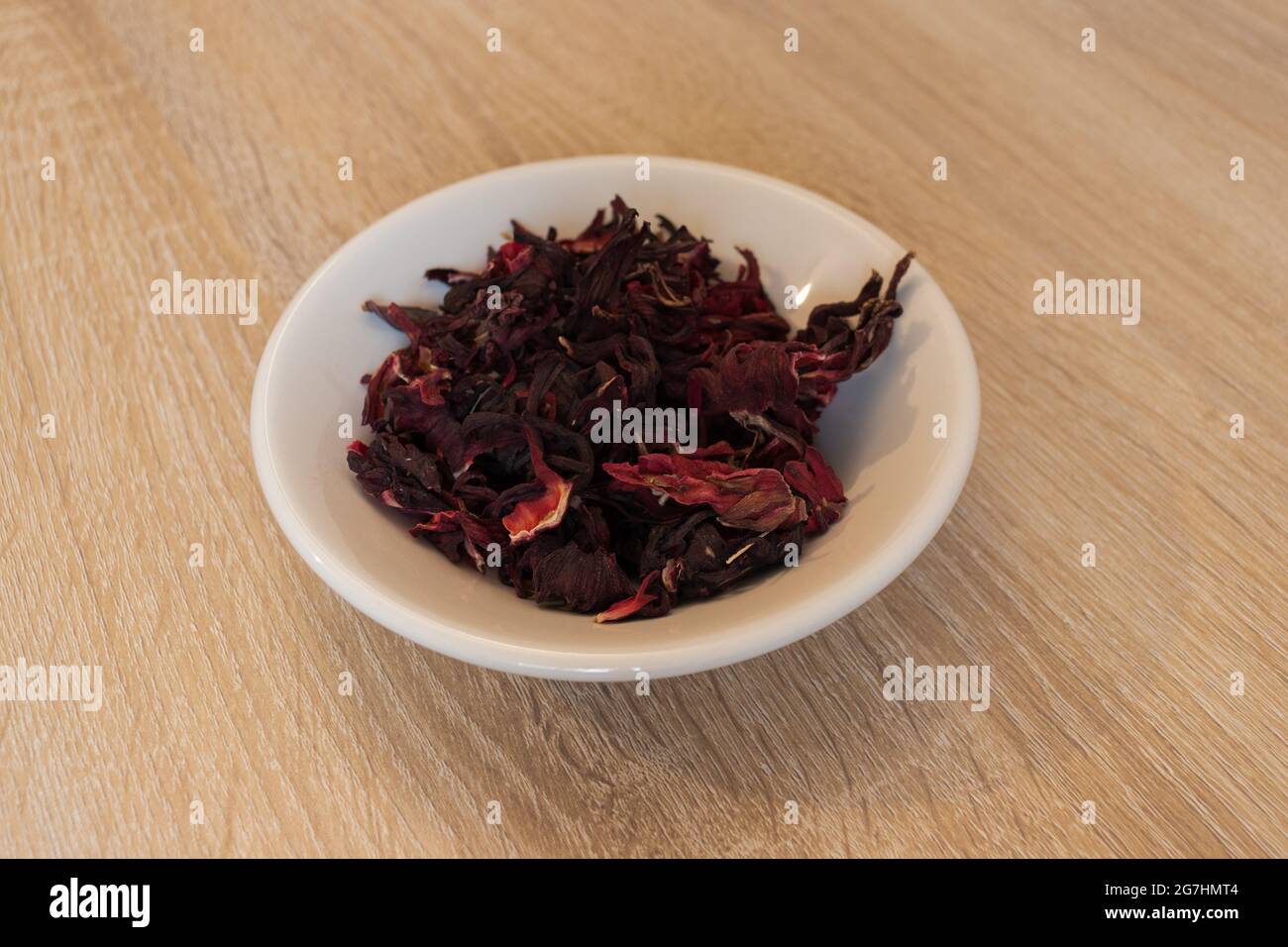 Roselle-Tee über einem weißen Teller. Weiße Schale mit Hibiskusblüte. Getrocknete Hibiskusblüte Stockfoto