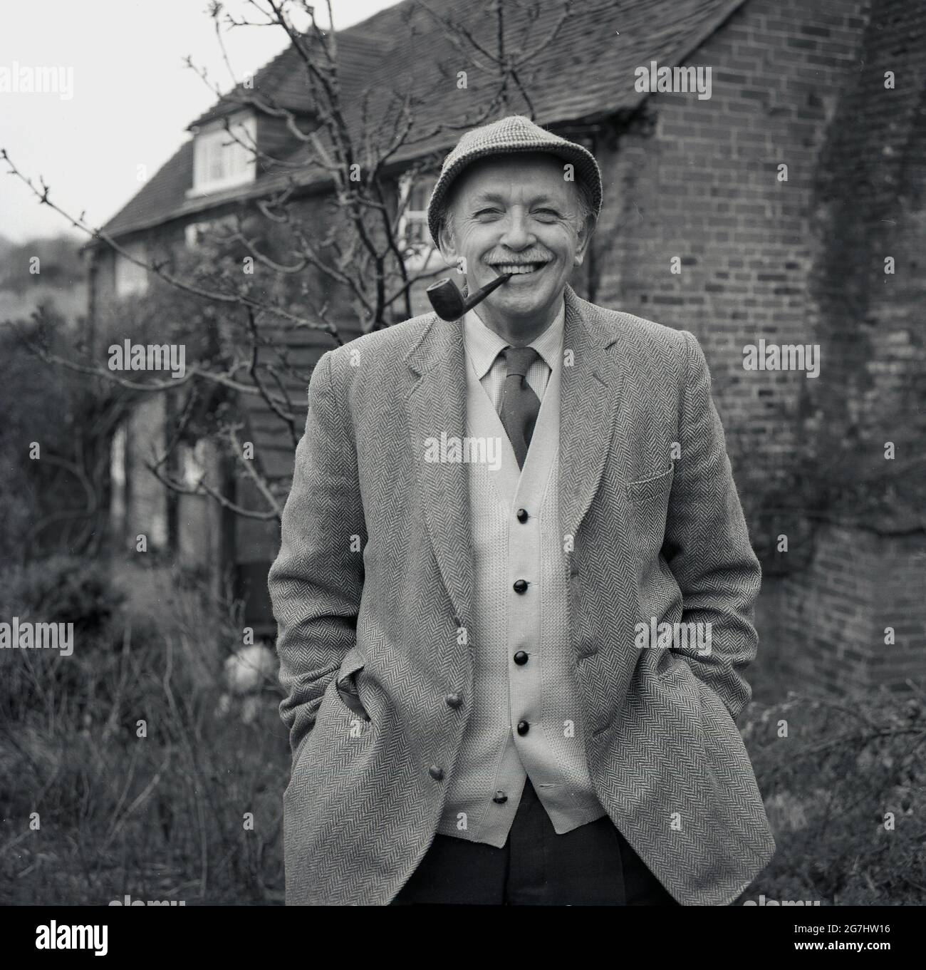 In den 1950er Jahren stand Brian Vesey-Fitzgerald vor seinem Häuschen. Ein Naturforscher und Autor von Büchern über Natur, Vögel und Hunde. Auch Herausgeber des Fachmagazins. Ein Nachkomme der Vesty-Fitzgeralds, einer berühmten angoirischen Familie, deren Mitglieder Abgeordnete sowohl in der britischen als auch in der irischen Regierung waren. Geboren 1905 in Wrexham, Denbighshire, Wales, als Brian Percy Seymour Vesey Fitzgerald. Wie viele seiner Generation liebte er seinen Tabak und wird hier mit seiner Pfeife und traditonaler Landkleidung einer Tweed-Jacke und Krawatte mit Strickjacke und Hut gesehen. Er war eine Autorität in der Geschichte der Zigeuner in Großbritannien. Stockfoto In den 1950er Jahren stand Brian Vesey-Fitzgerald vor seinem Häuschen. Ein Naturforscher und Autor von Büchern über Natur, Vögel und Hunde. Auch Herausgeber des Fachmagazins. Ein Nachkomme der Vesty-Fitzgeralds, einer berühmten angoirischen Familie, deren Mitglieder Abgeordnete sowohl in der britischen als auch in der irischen Regierung waren. Geboren 1905 in Wrexham, Denbighshire, Wales, als Brian Percy Seymour Vesey Fitzgerald. Wie viele seiner Generation liebte er seinen Tabak und wird hier mit seiner Pfeife und traditonaler Landkleidung einer Tweed-Jacke und Krawatte mit Strickjacke und Hut gesehen. Er war eine Autorität in der Geschichte der Zigeuner in Großbritannien. Stockfoto
