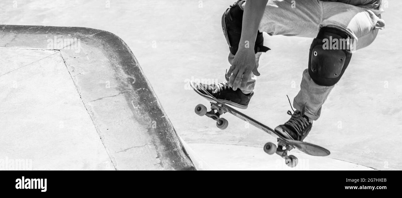 Graustufen-Action-Aufnahme der Füße des Skateboarders beim Skaten Stockfoto