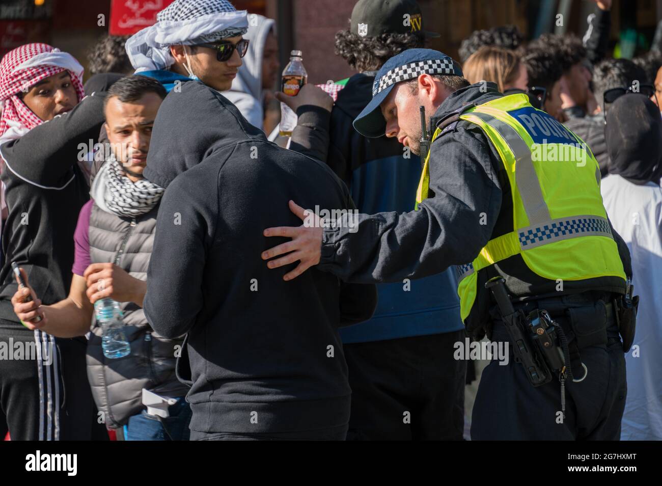 LONDON - 29. MAI 2021: Ein britischer Polizeibeamter stellt bei einer Protestkundgebung für Freiheit für Palästina in London einen Mann in einem schwarzen Hoodie in Frage Stockfoto